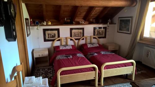 twee bedden in een kleine kamer met rode lakens bij B&B San Giorgio in Sovramonte