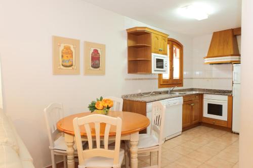 a kitchen with a wooden table and chairs and a kitchen with a sink at Apartamentos Albá Casa Alquesera in Sahun