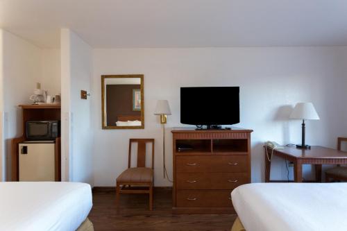a hotel room with two beds and a television on a dresser at Vagabond Inn Executive in Green Valley