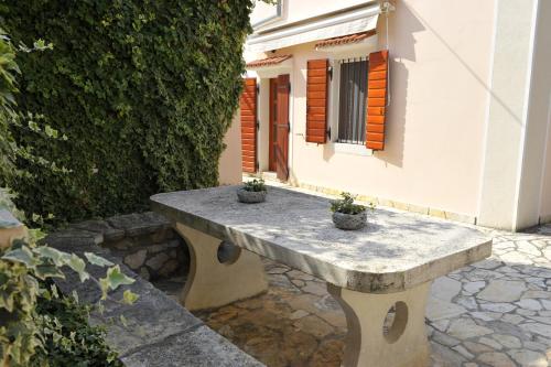 a stone bench in front of a building with two potted plants at Grandpa Mate House in Dragove
