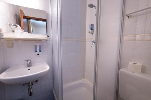 ein weißes Bad mit einem Waschbecken und einer Dusche in der Unterkunft Atlanta Budget in Darmstadt