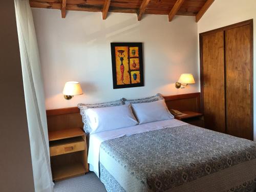 Un dormitorio con una cama con dos lámparas encima. en Onais Hotel, en Mar de Ajó