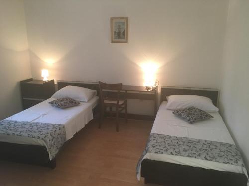 two beds in a room with a table and a desk at Apartmani Josipa in Šibenik