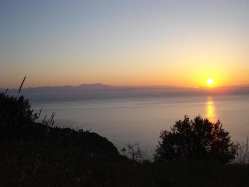 a sunset over the water with the sun in the sky at Studios Kyparissi & Spa in Tiros