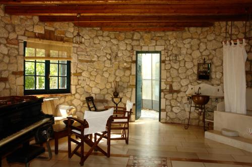 a living room with a stone wall and a piano at Musician's Round House & Castello in Vátos