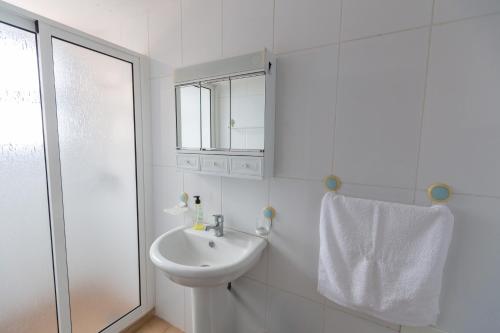 Un baño blanco con lavabo y ducha. en Casa do Avo, en Arco da Calheta