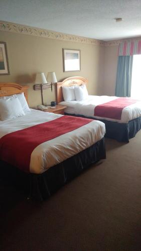 a hotel room with two beds with red sheets at Country Inn & Suites by Radisson, Waterloo, IA in Waterloo