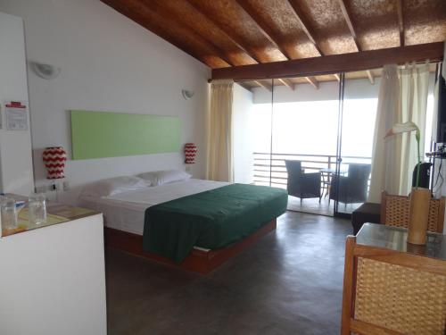a bedroom with a bed with a green bedspread at Akas Hotel Apartamentos in Canoas De Punta Sal