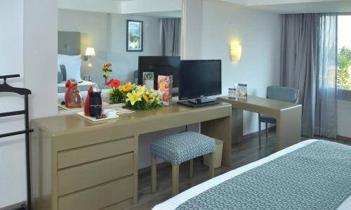 a hotel room with a desk with a television and a bed at Best Western PLUS Gran Hotel Morelia in Morelia