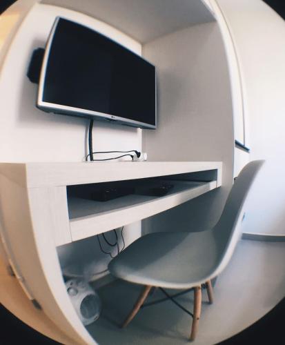 a computer desk with a monitor and a chair at Apartamento Completo em Cotia - SP in Cotia