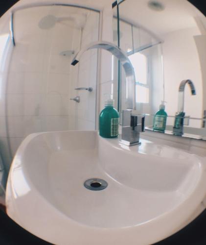 a white bathroom sink with a mirror and green soap at Apartamento Completo em Cotia - SP in Cotia