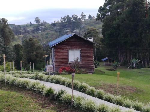 a small building with a field of plants in front at Hotel Campestre El Refugio de Balsora in Filandia