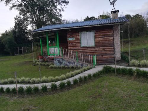 a log cabin with a solar roof on a hill at Hotel Campestre El Refugio de Balsora in Filandia