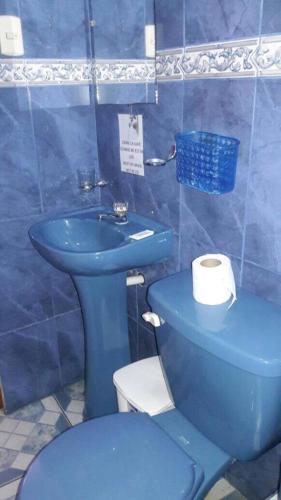a blue bathroom with a toilet and a sink at Hostal Gosén in Puerto Baquerizo Moreno