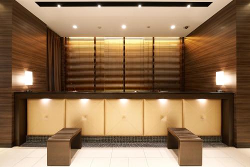a lobby with two benches in front of a counter at Sotetsu Fresa Inn Chiba Kashiwa in Kashiwa