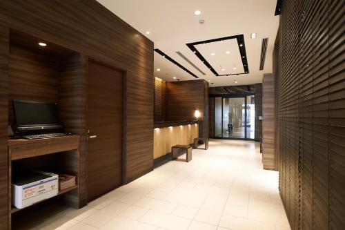 an office lobby with wood paneling and a television at Sotetsu Fresa Inn Chiba Kashiwa in Kashiwa