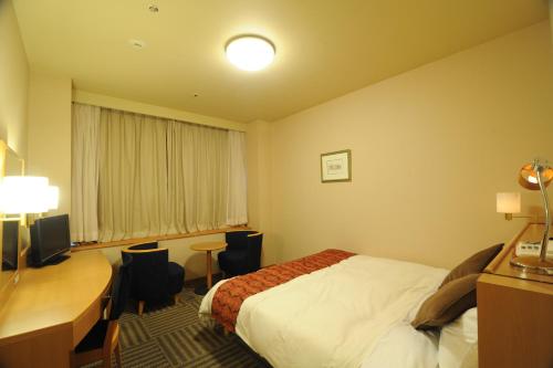 a hotel room with a bed and a desk at Yamagata Eki Nishiguchi Washington Hotel in Yamagata