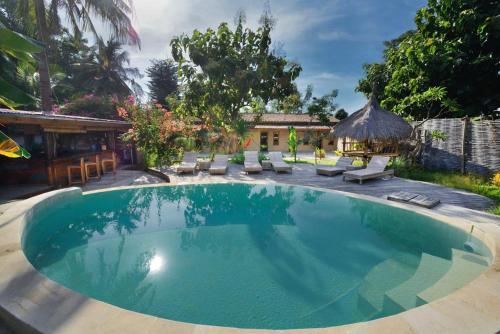 a large swimming pool with chairs and a house at Jati Village, Party Hostel and Bungalows in Gili Trawangan