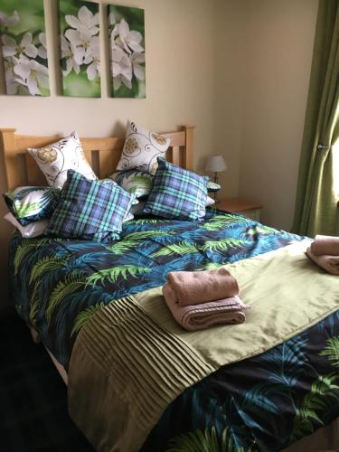 1 cama con almohadas y manta azul y verde en Christiesholidayhomes en Aviemore