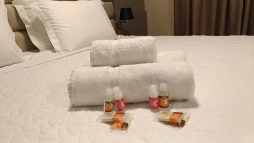 a pile of towels on a bed with two bottles of alcohol at Paracambi Top Hotel in Paracambi