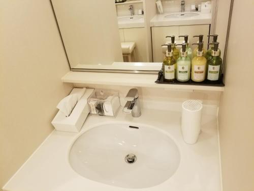 a bathroom sink with bottles of wine on a shelf at Glansit Akihabara in Tokyo