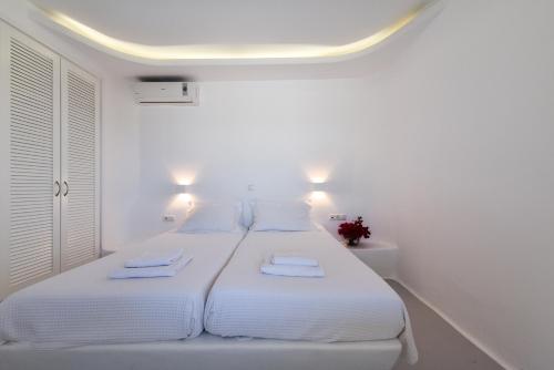 a white bedroom with two beds with towels on them at Cavos in Agios Sostis