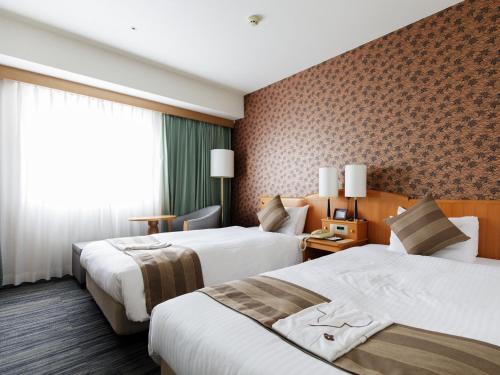 a hotel room with two beds and a window at Okayama Koraku Hotel in Okayama