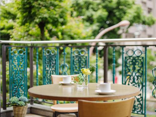 un tavolo con due tazze e un vaso con fiori sul balcone di Okayama Koraku Hotel a Okayama