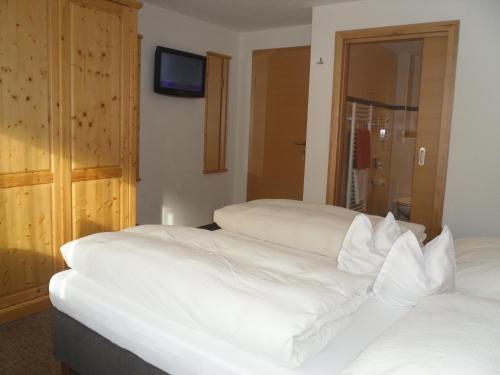 a bedroom with two beds and a tv on the wall at Grünwaldhof in Tux