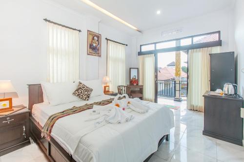 een slaapkamer met een bed met witte lakens en een televisie bij Yoga's House in Ubud