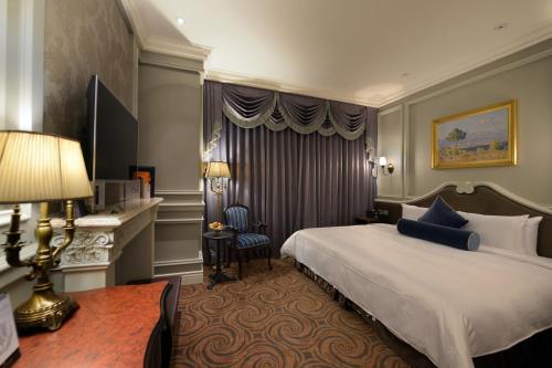 a hotel room with a large bed and a desk at Golden Tulip RS Boutique Hotel-Tainan in Tainan