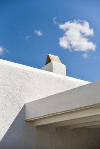a bird sitting on top of a white building at Cavos in Agios Sostis