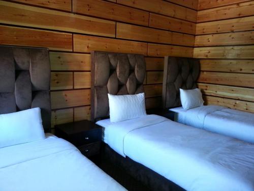 two beds in a room with wooden walls at L'empreinte D'ifrane in Ifrane