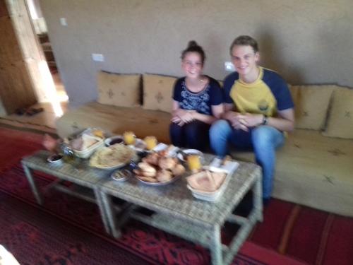 two women sitting on a couch with a table with food at Kasbah Izoran in Midelt