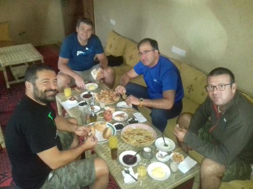 a group of men sitting around a table eating food at Kasbah Izoran in Midelt