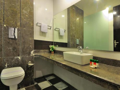 a bathroom with a sink and a toilet and a mirror at Hotel Elegance in New Delhi