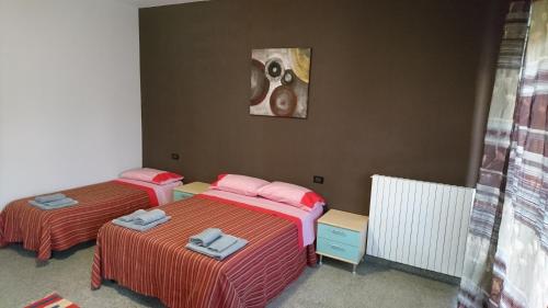 ミラノにあるL'Isola di Romyのベッド2台が備わる客室で、壁には絵画が飾られています。