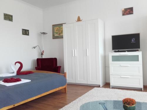 a bedroom with a bed and a tv and a cabinet at Éger Apartman in Eger