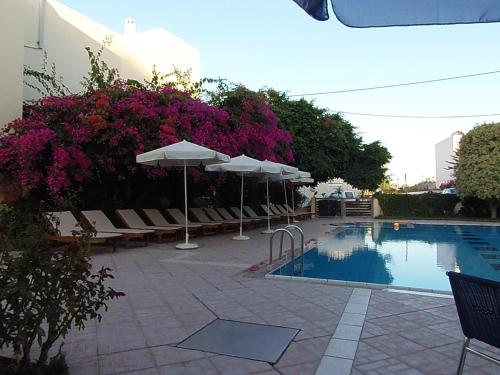 a pool with chairs and umbrellas next to a building at Atlantica Yakinthos in Kato Daratso