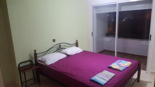 a bedroom with a purple bed with a window at Golf View Marina in Asilah