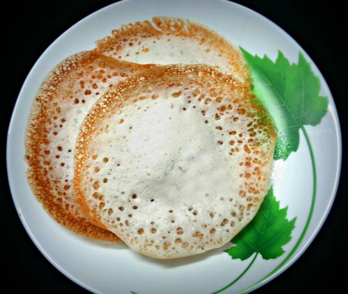 a white plate with a pancake on top at Sterling Guruvayur in Guruvāyūr