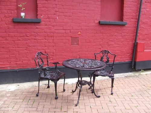 two chairs and a table in front of a red wall at Alexandra Guest House in Hemel Hempstead