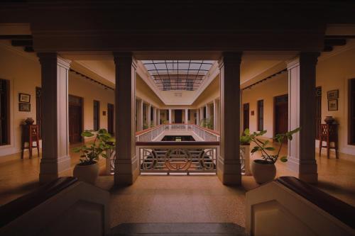 Chettinadu的住宿－Visalam Chettinad Palace - CGH Earth，建筑里大走廊上,有盆栽植物