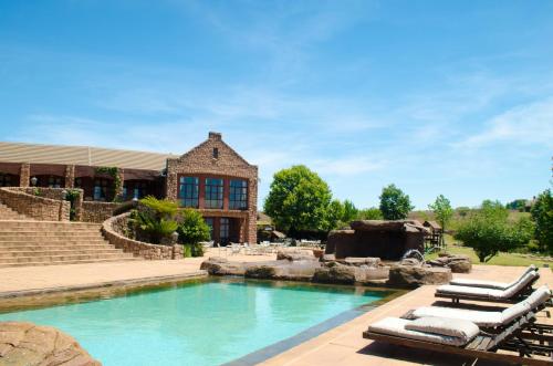 a swimming pool with lounge chairs in front of a house at Gooderson Kloppenheim Country Estate in Machadodorp