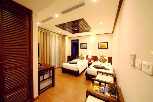 a hotel room with two beds and a table at Hanoi Nostalgia Hotel & Spa in Hanoi