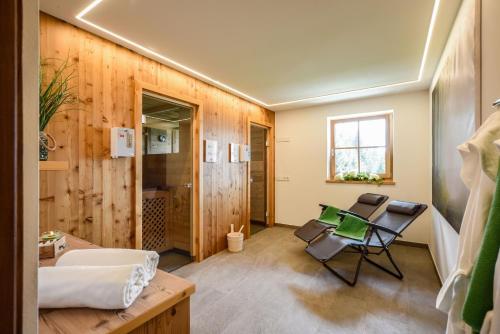 Habitación con baño con paredes de madera y silla. en Chalet Flierer en Rodengo