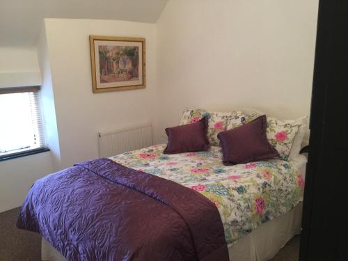 a bedroom with a bed with purple sheets and purple pillows at Cottage on the Green in Brackley