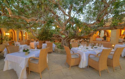 a restaurant with white tables and chairs under a tree at Hotel Ta' Cenc & Spa in Sannat