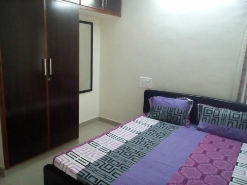 um quarto com uma cama com lençóis e almofadas roxos em G k Homestay em Tirupati