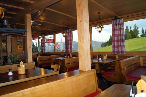 ein Restaurant mit Holztischen, Bänken und Fenstern in der Unterkunft Alpengasthof Brüggele in Alberschwende